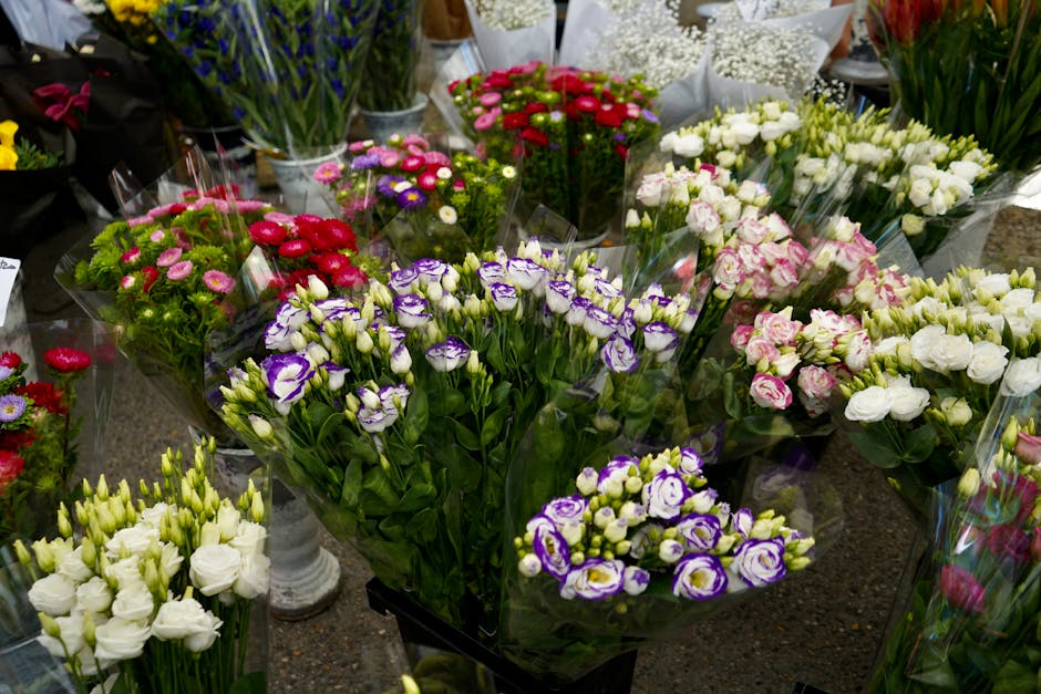 A diverse display of fresh floral arrangements and bouquets featuring a variety of flowers such as purple and white lisianthus, pink and white roses, and small daisy-like blooms in shades of red, pink
