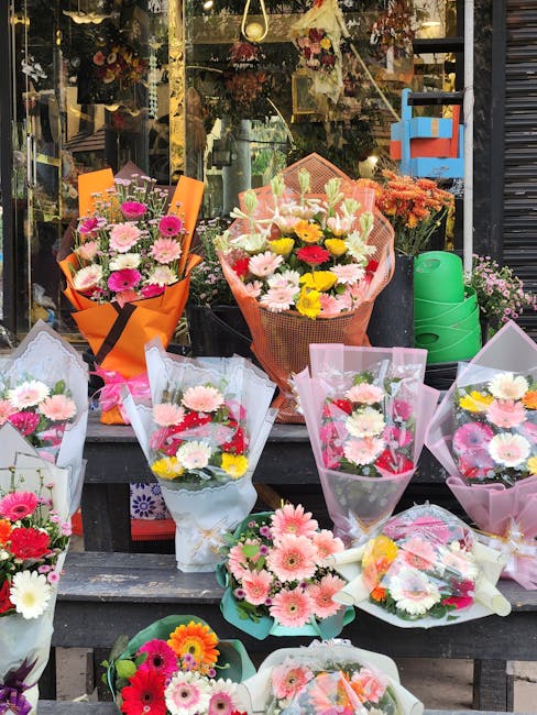 A variety of fresh flower bouquets displayed outside South Kensington florist, featuring a mix of pink, white, yellow, and red daisies, chrysanthemums, and lilies, wrapped in colorful papers and trans